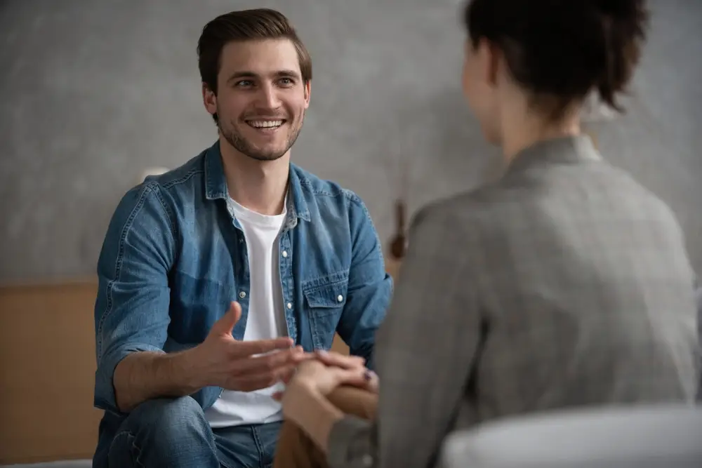 Psychologist talking with patient on therapy session. Depressed man speaking to a therapist while she is taking notes